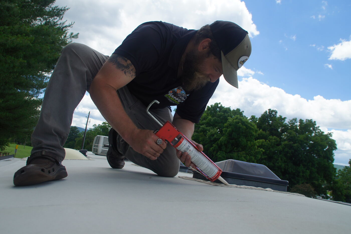 Happy Camper technician applying sealant to an RV roof seam to stop leaks